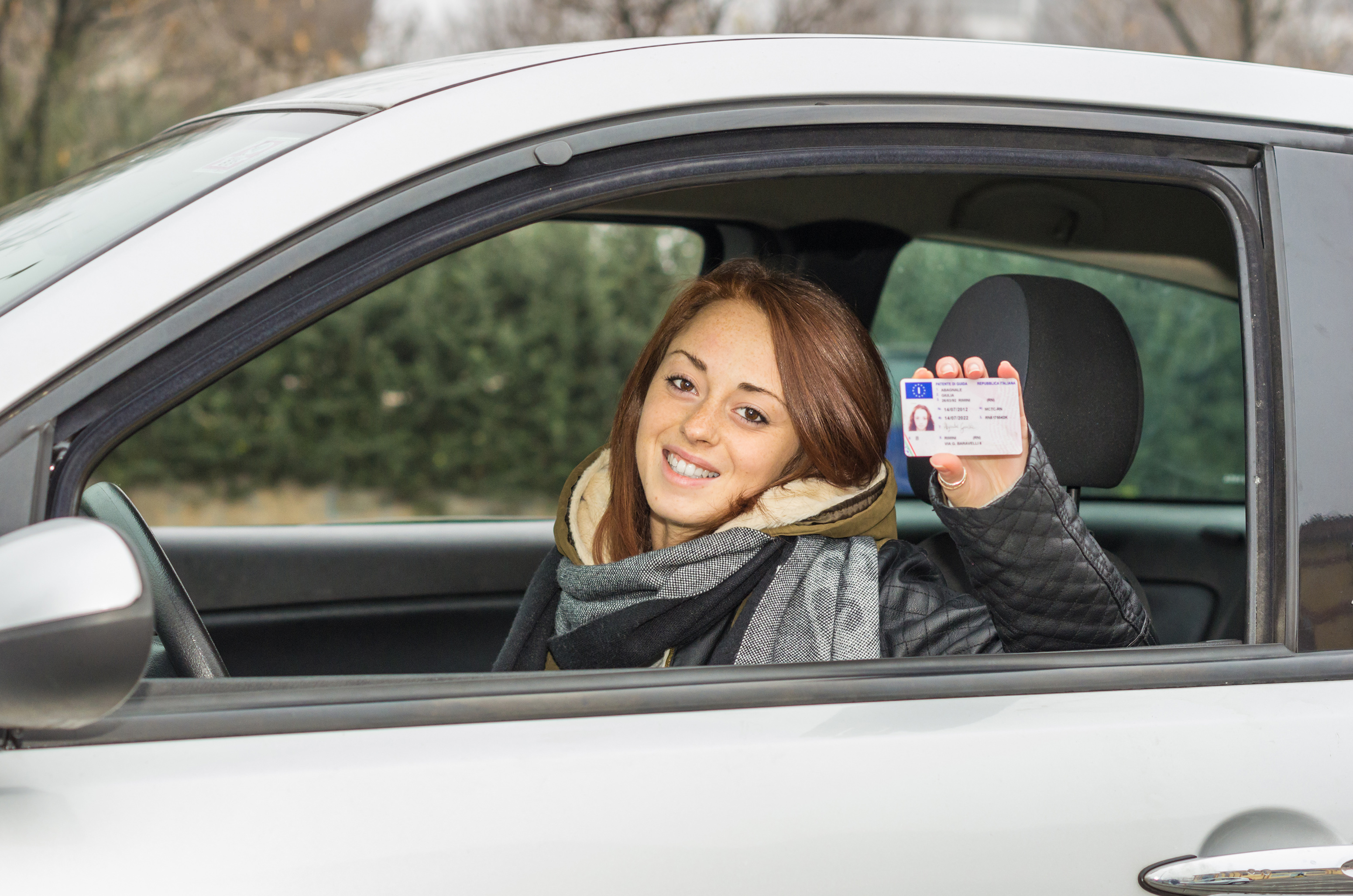 girl in the car smiling happy showing her driver's license - caucasian people